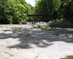 Bridge End Footbridge from the east showing limestone slabs in the river bed
